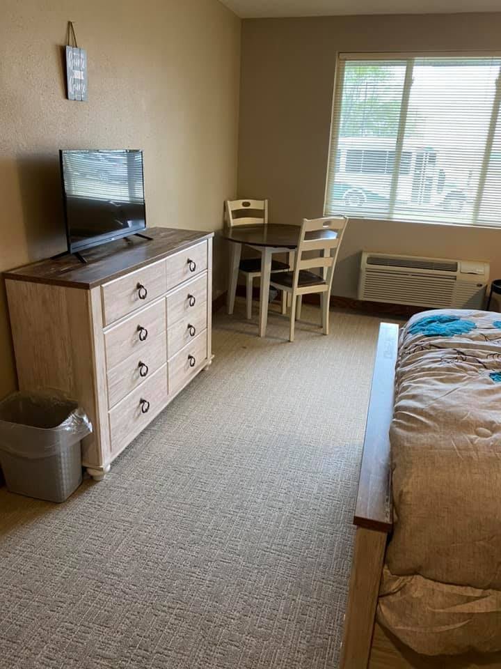 Cozy bedroom with a dresser, TV, and seating area by the window.