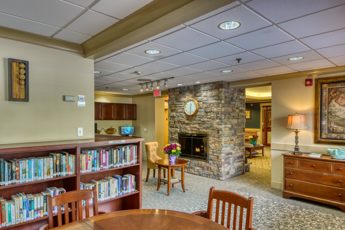 A cozy lounge area with bookshelves, a fireplace, and seating arrangements.