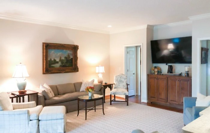 A cozy living room featuring a comfortable sofa, a wall-mounted television, and elegant artwork.