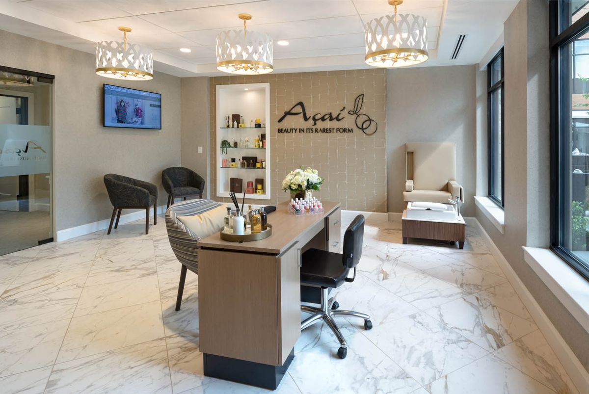 A modern office interior with elegant decor, featuring a desk, chairs, and chandeliers.