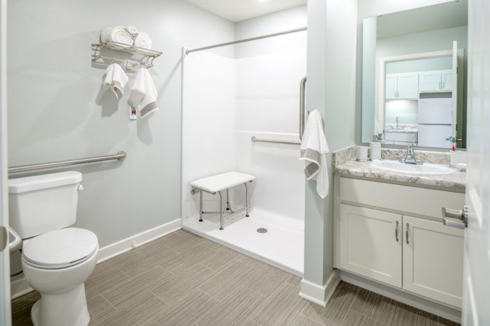 An accessible bathroom with safety features such as grab bars and a shower seat.