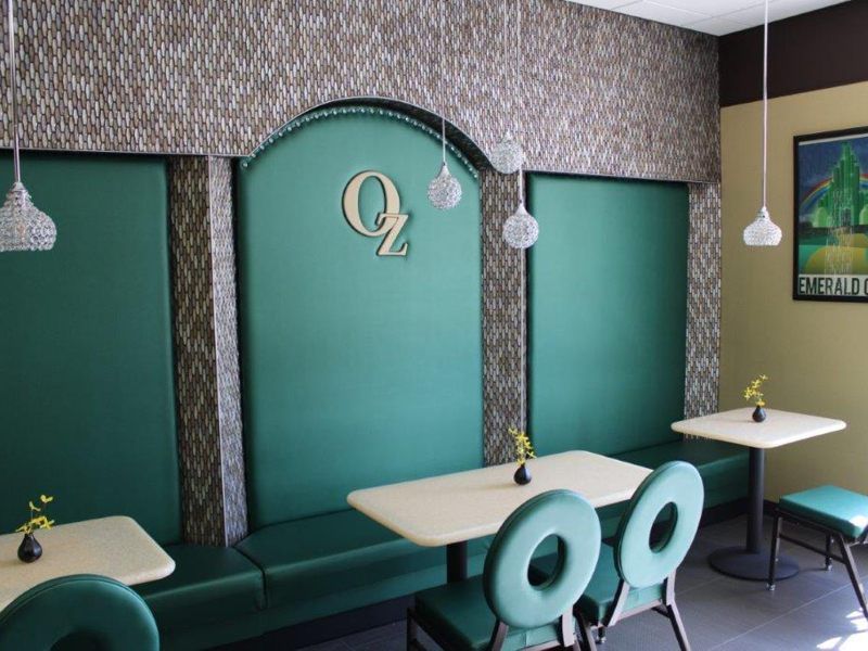 A modern restaurant interior featuring a green color scheme with stylish seating and pendant lighting.