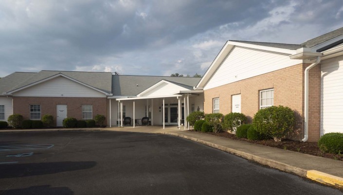 A view of a building with a white entrance and cloudy skies above.