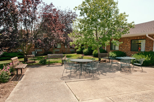 A serene outdoor courtyard featuring tables and benches surrounded by lush greenery.