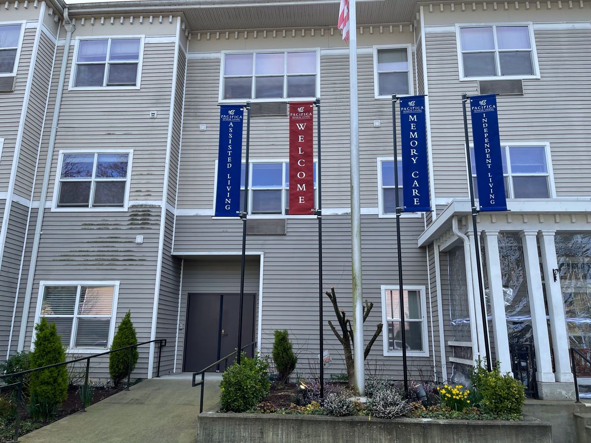 An entrance to a modern apartment building adorned with multiple flags.