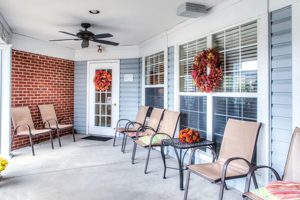 A cozy porch decorated with autumn wreaths and comfortable outdoor seating.