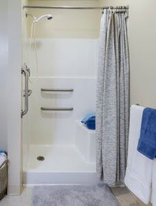 A clean and organized bathroom shower area with a curtain and towels.