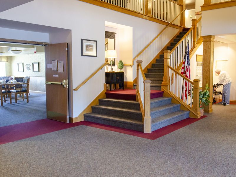 A well-lit interior space with a staircase, carpeted floor, and decorative elements.