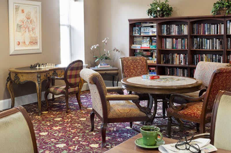 A cozy library reading room with bookshelves, tables, and chairs.