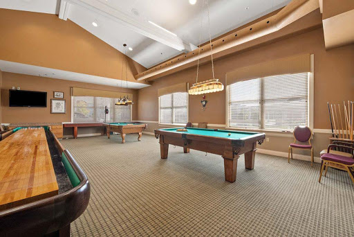 A spacious game room featuring billiards tables and large windows.