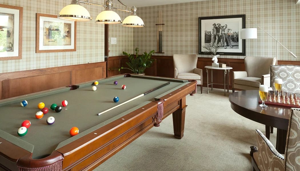 A cozy game room featuring a pool table with billiard balls and cues, surrounded by elegant interior decor.