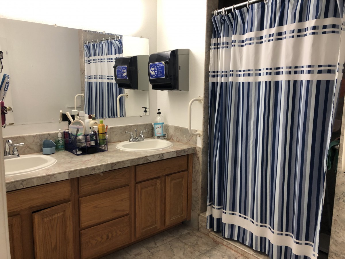 A bathroom with a double sink vanity and blue striped shower curtain.