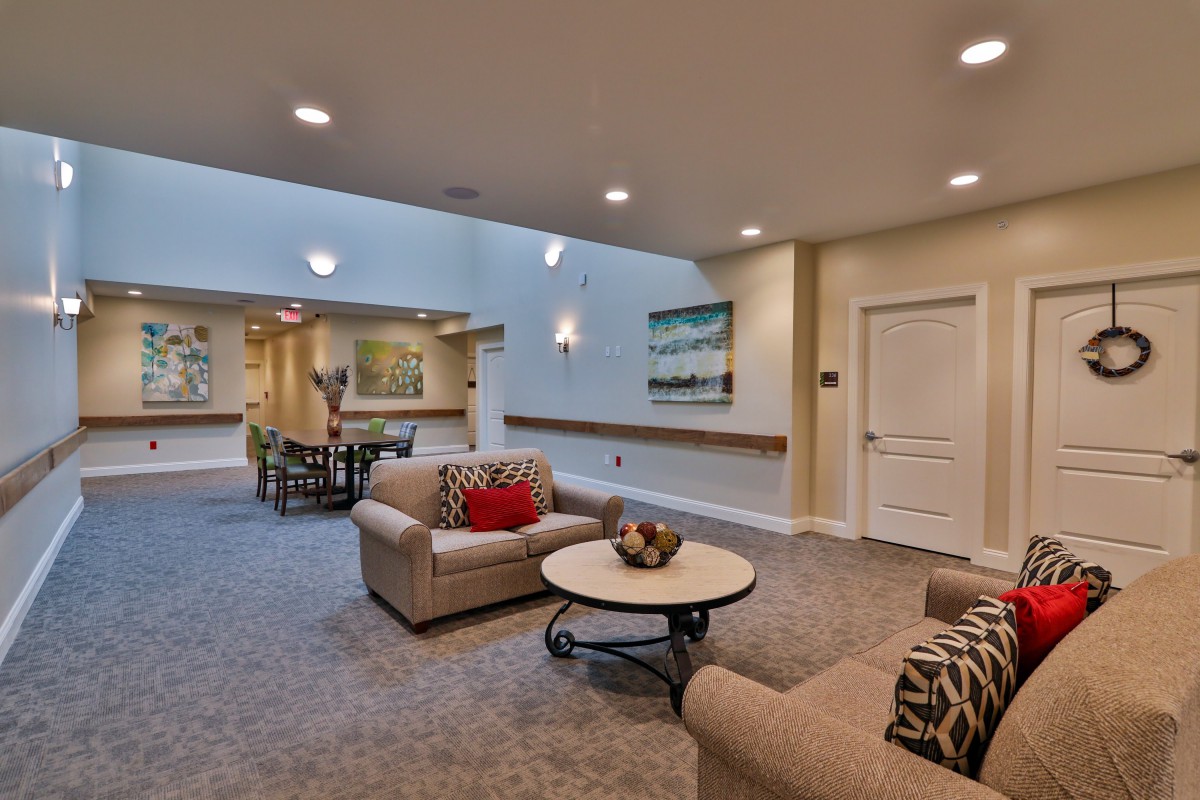 A modern living room interior with sofas, a round table, and artwork on the walls.