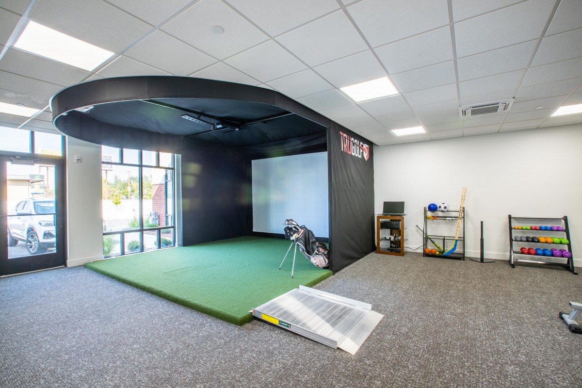 An indoor golf simulator setup with a practice area and sports equipment.