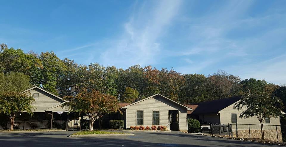 A small residential building surrounded by trees under a clear blue sky.