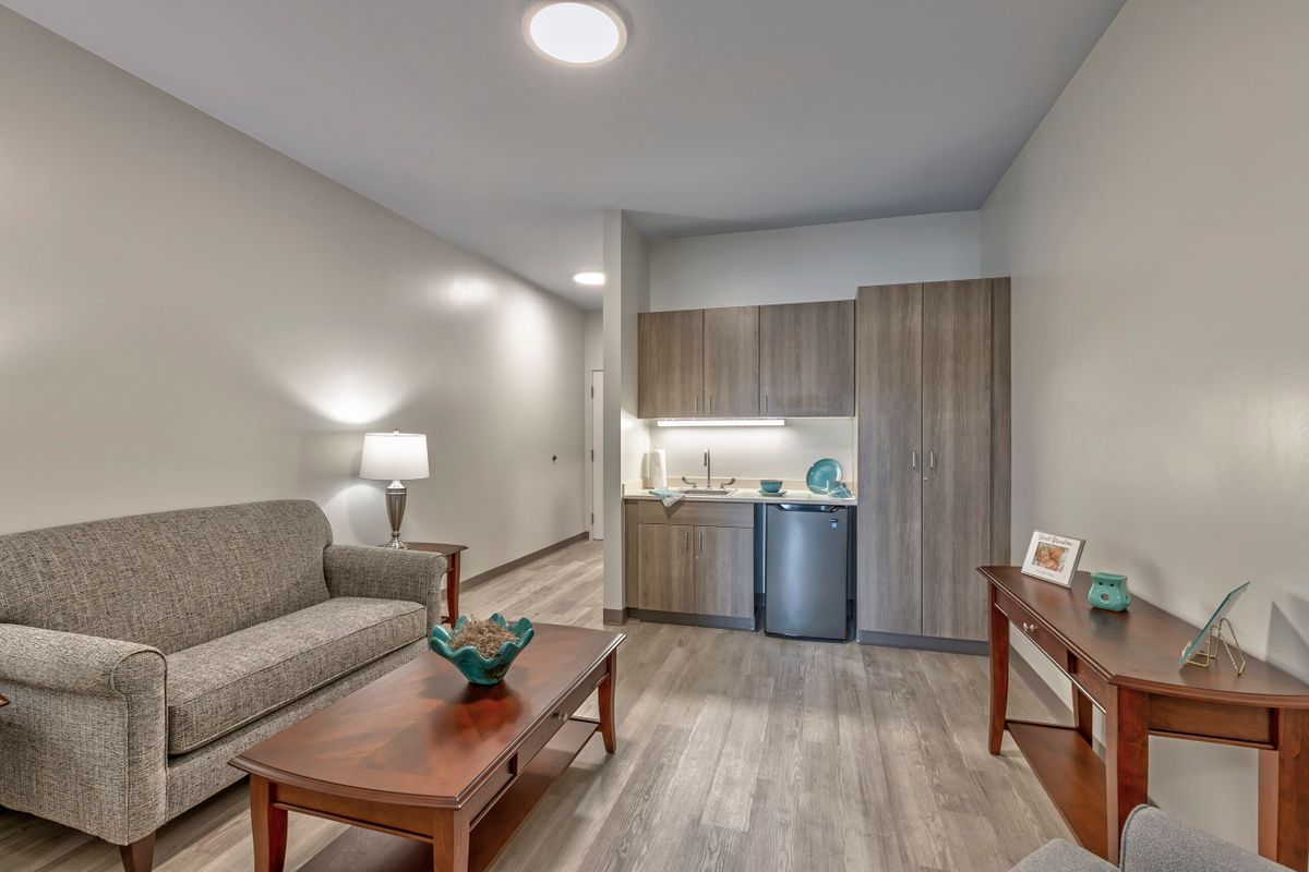 A modern apartment living space with a cozy sofa, coffee table, and compact kitchenette.
