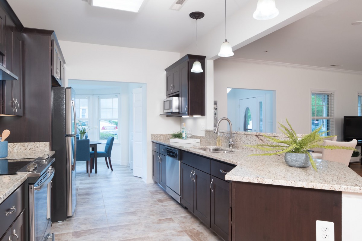 A modern kitchen with dark cabinets, sleek countertops, and contemporary lighting.