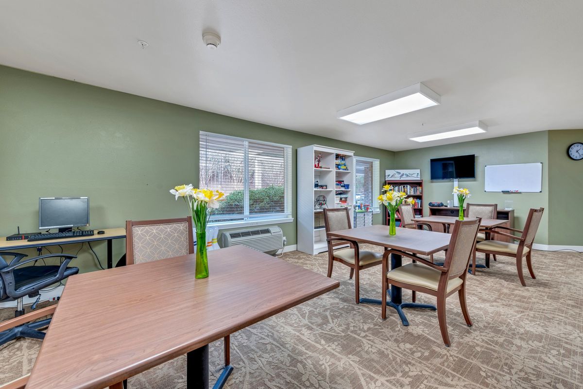 A calm dining area with wooden tables, chairs, and decorative flowers in vases.