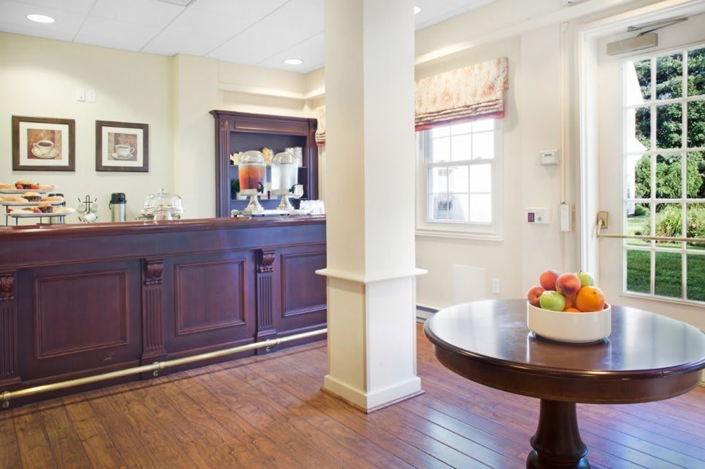 A cozy reception area with a wooden counter and a fruit bowl on a table.