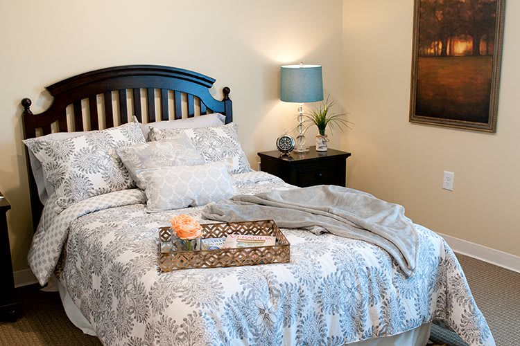 A cozy bedroom with patterned bedding and a bedside lamp.