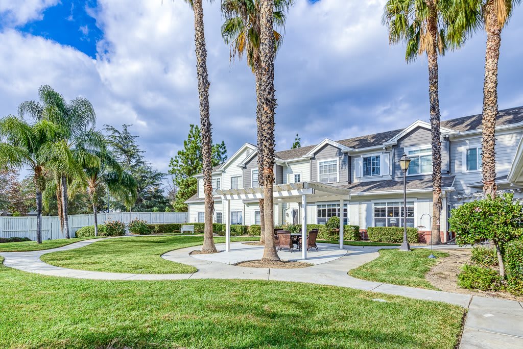 A suburban residential building surrounded by palm trees and a well-maintained green lawn under a cloudy sky.