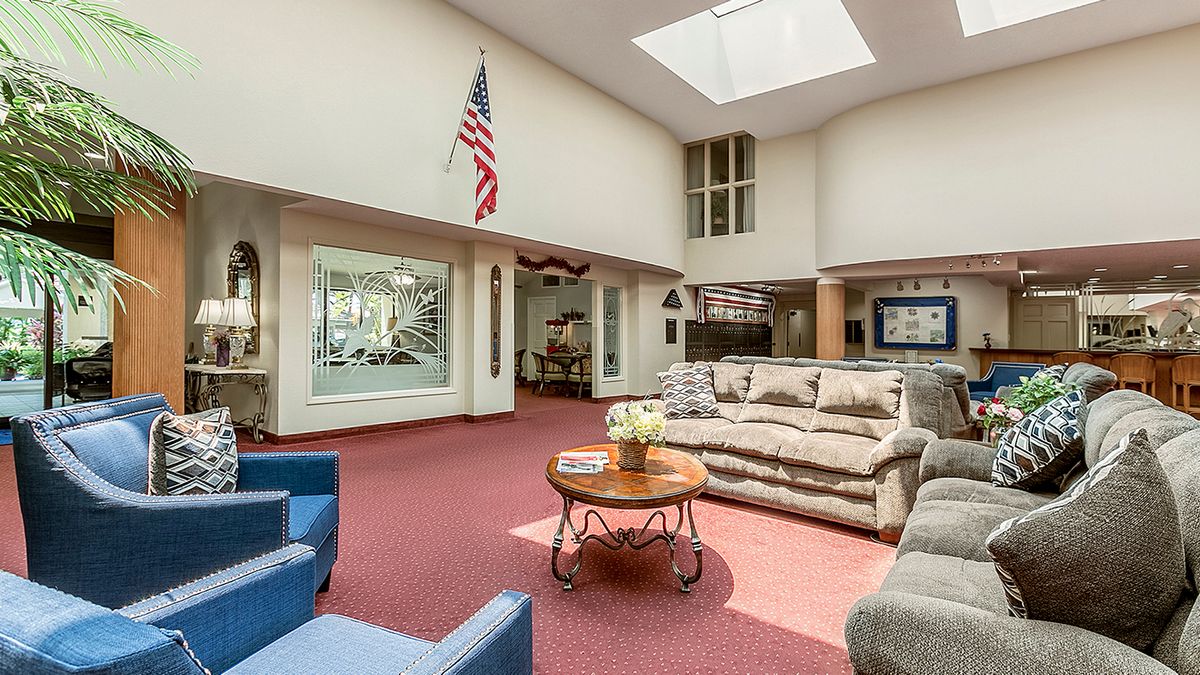 A spacious living room with comfortable sofas, a coffee table, and a large skylight, adorned with an American flag.