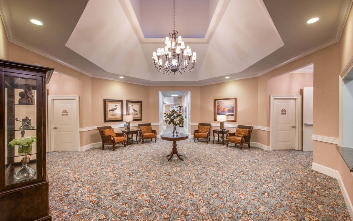 A spacious lobby with elegant decor, featuring a chandelier and comfortable seating.