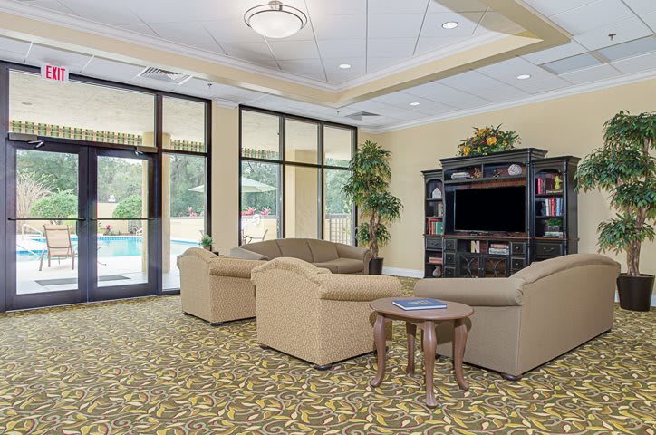 A cozy living room with comfortable sofas, a TV, and large windows.