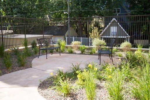 A serene garden area featuring curved pathways and benches surrounded by lush greenery.