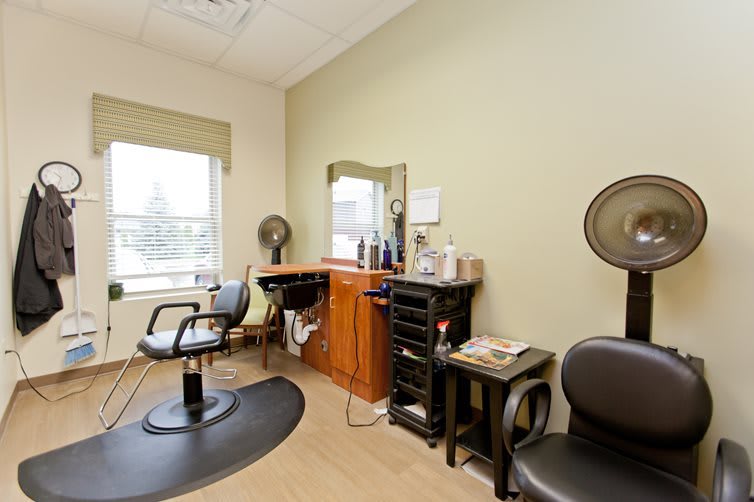A cozy hair salon interior with styling chairs, a mirror, and various hairdressing tools.