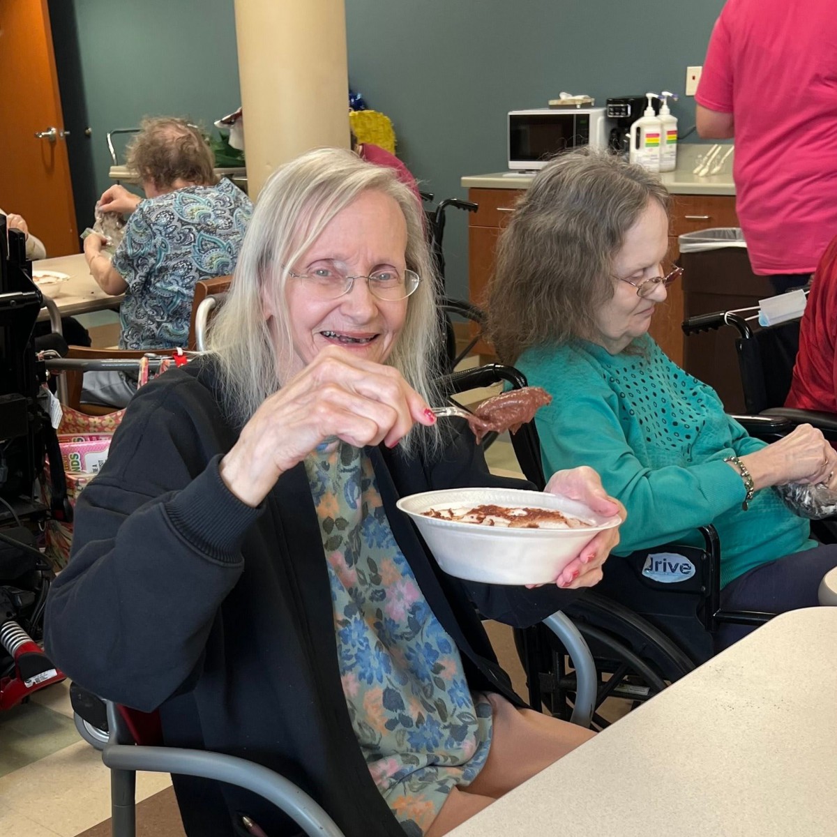 Elderly women enjoy a meal together in a care facility setting.