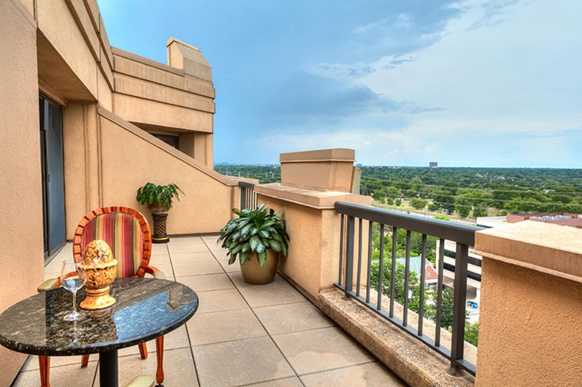 A cozy balcony with scenic views and comfortable seating, featuring decorative plants and a vibrant chair.
