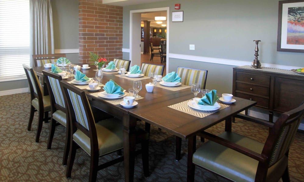 An elegantly set dining table with neatly arranged chairs and turquoise napkins.