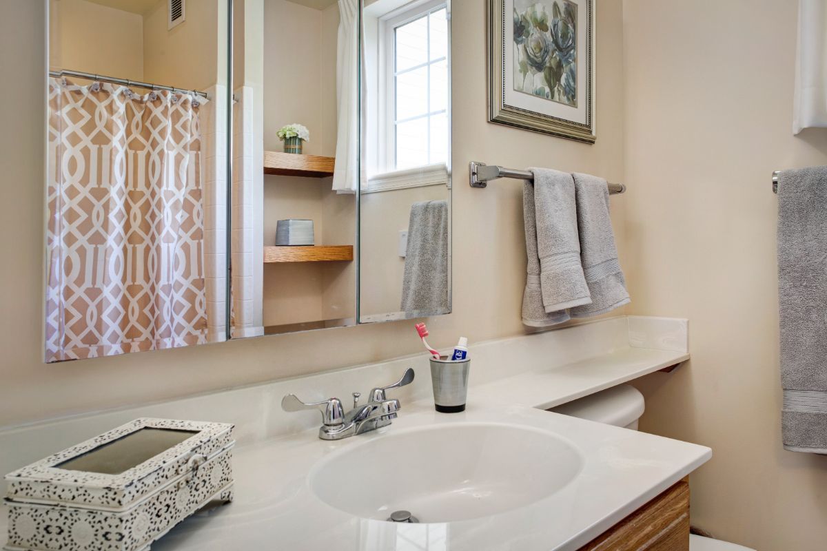 A tidy bathroom with a sink, mirror, and neatly arranged towels.