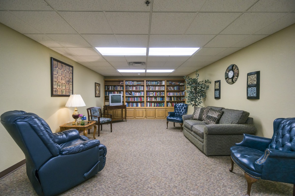A cozy living room with comfortable seating, a television, and bookshelves lining the wall.