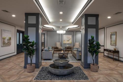A modern lobby featuring a central fountain, surrounded by seating areas and plants.