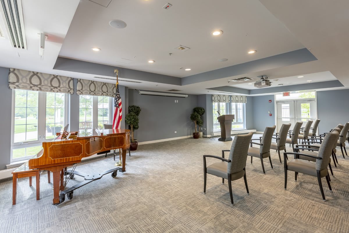 A well-lit conference room setup with chairs, a podium, and an American flag near the windows.