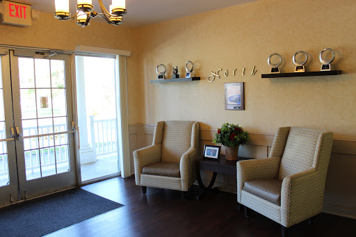 A cozy waiting area featuring comfortable chairs, decorative trophies, and natural light.