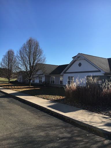 A peaceful residential building surrounded by trees under a clear blue sky.