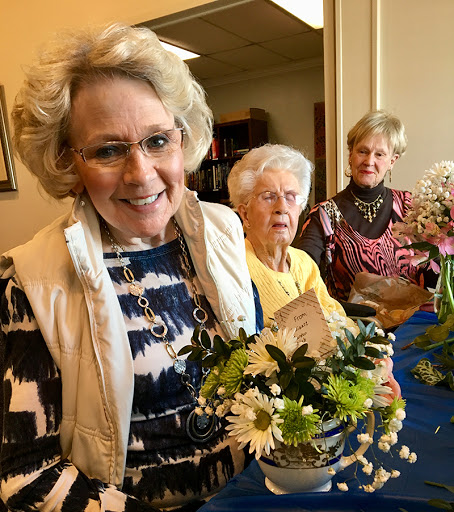 A joyful gathering of women showcasing their floral arrangements.