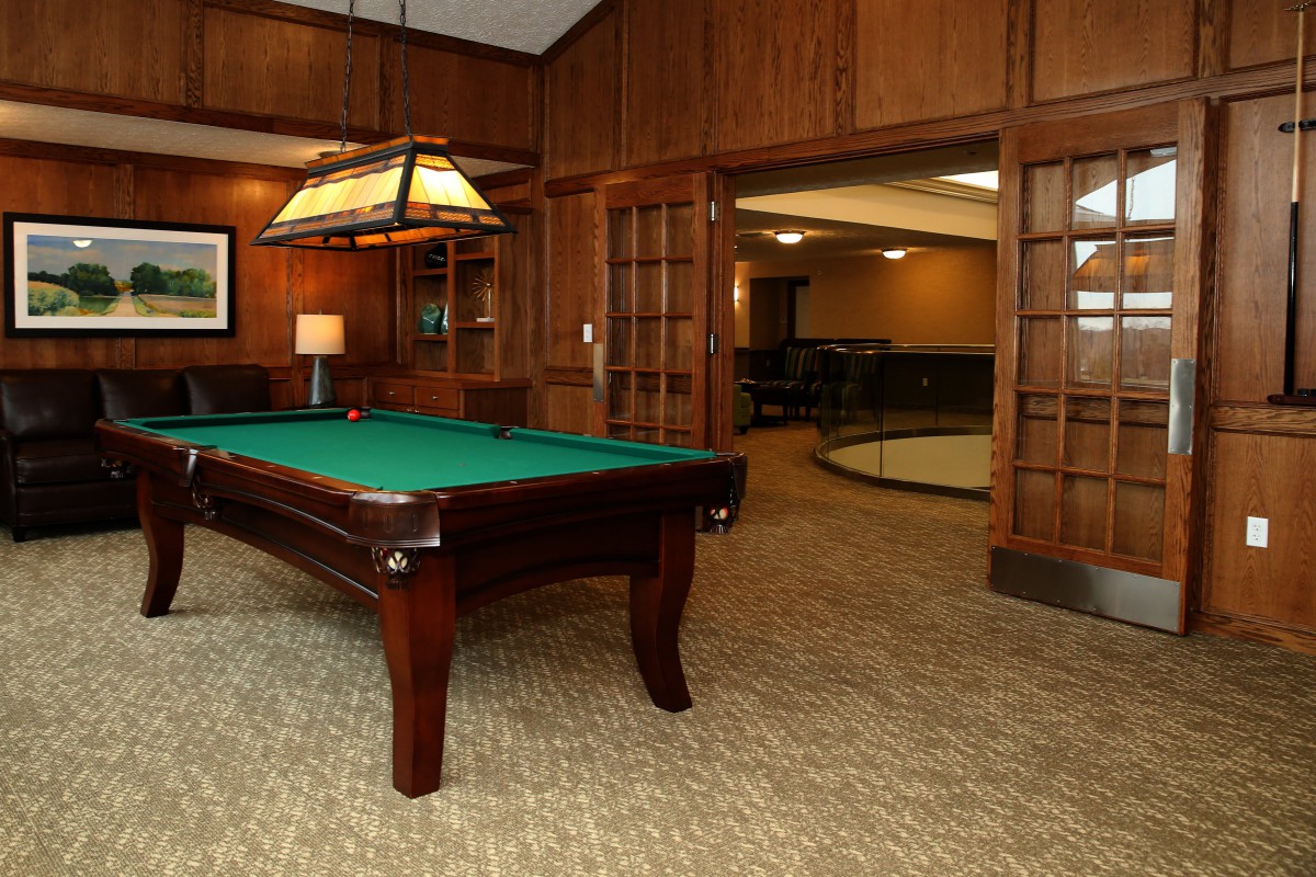 Cozy billiard room with a classic pool table and warm wood paneling.