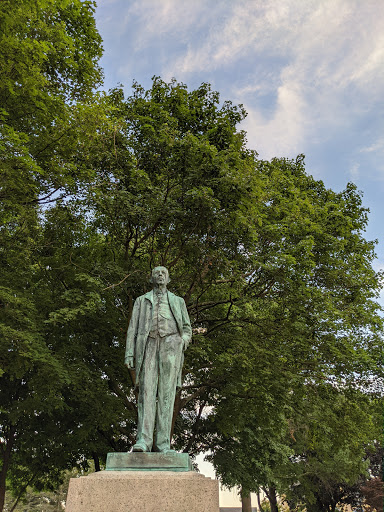 A statue surrounded by lush greenery, standing tall against a clear sky.