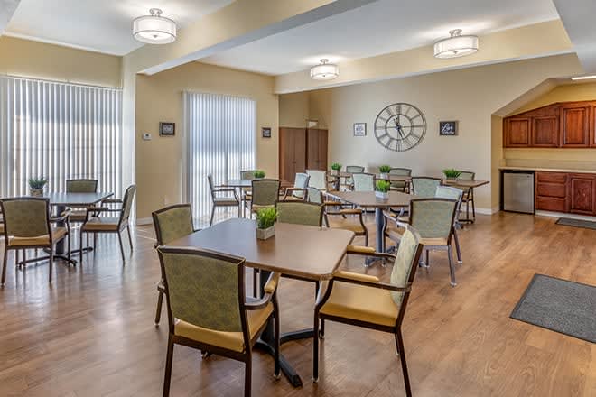 A modern dining area with neatly arranged tables and chairs, illuminated by stylish ceiling lights.