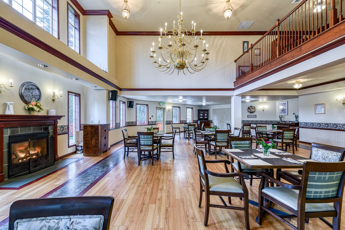A spacious, well-lit dining area with elegant chandeliers and neatly arranged tables and chairs.