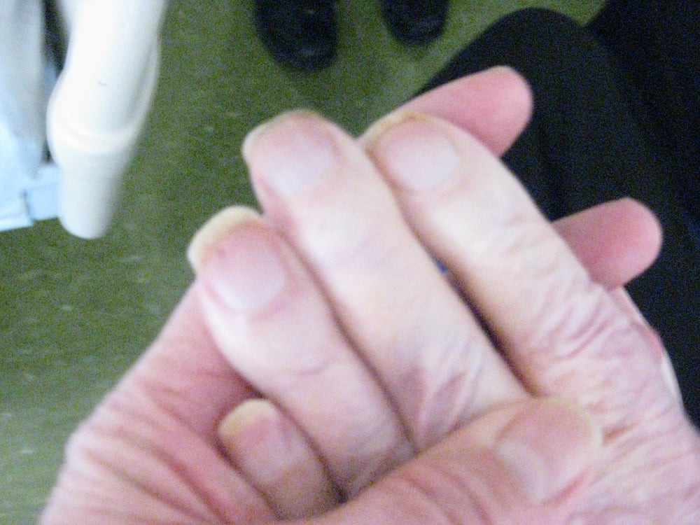 An elderly hand is gently held, signifying care and support.