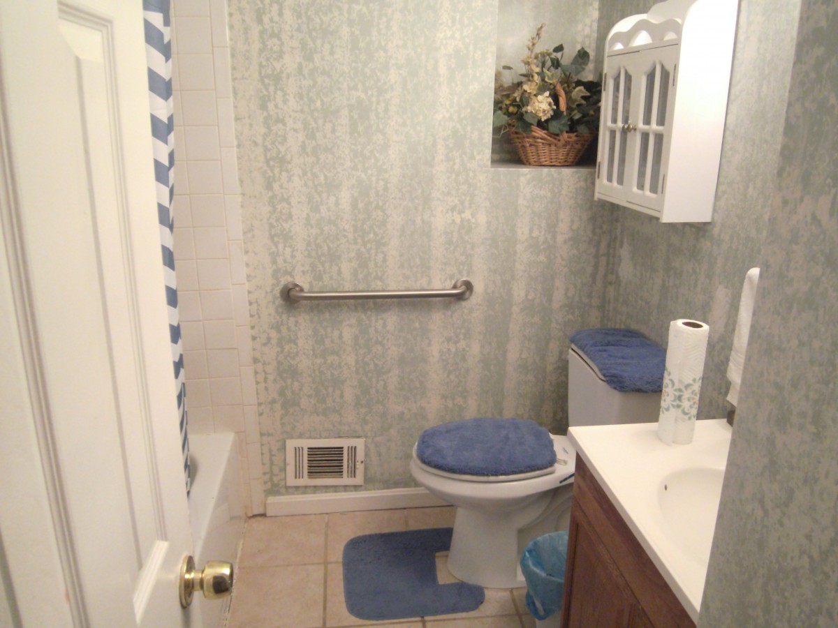 A cozy bathroom with blue accents, featuring a toilet, sink, and towel rack.
