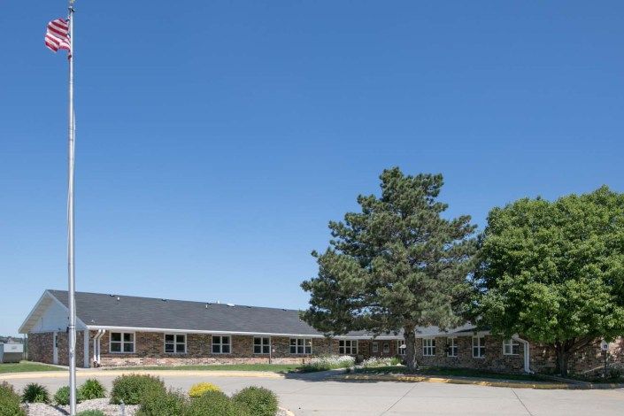 A wide view of a school building with trees and a clear blue sky.