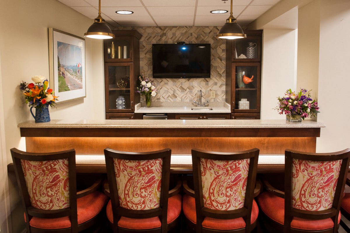 A cozy bar area with upholstered chairs, a countertop, and ambient lighting.