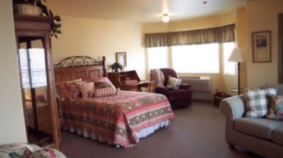 A cozy bedroom featuring a large bed, an armchair, and a window with natural light.