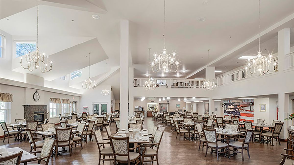An elegant dining area with chandeliers and neatly arranged tables and chairs.